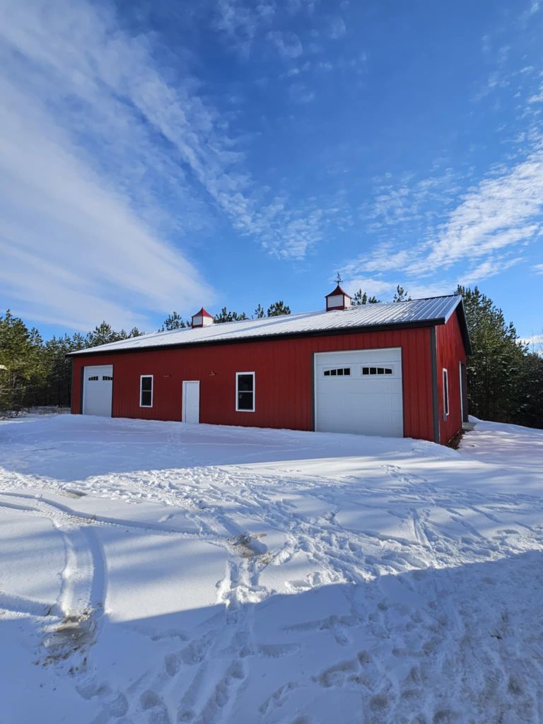 Red barn in winter scene with snow on the ground.
