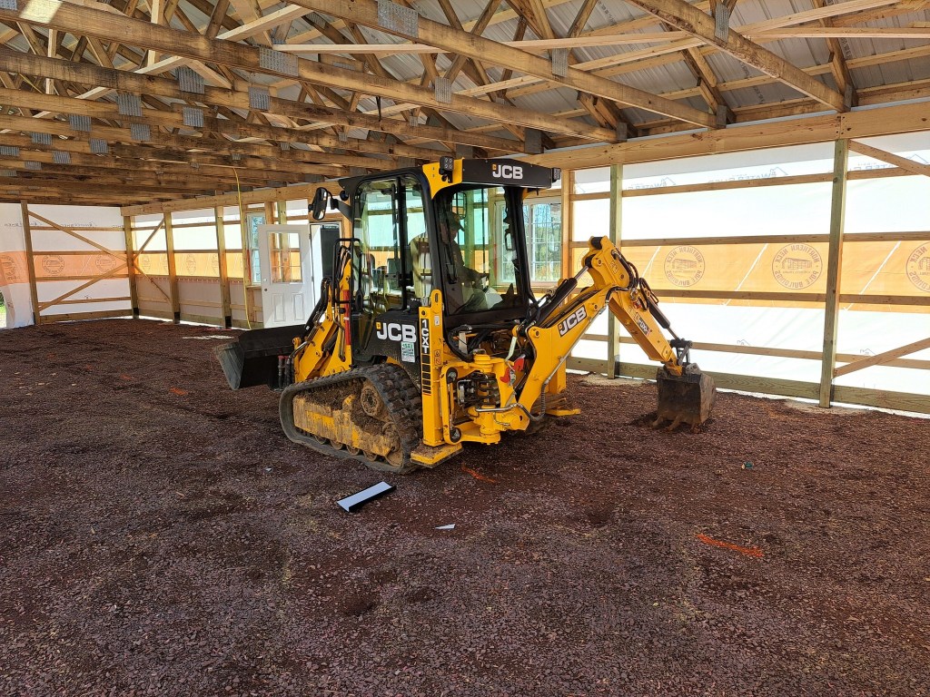 The image features a yellow JCB backhoe excavator with a black body, prominently displaying the brand name 'JCB' in white ...