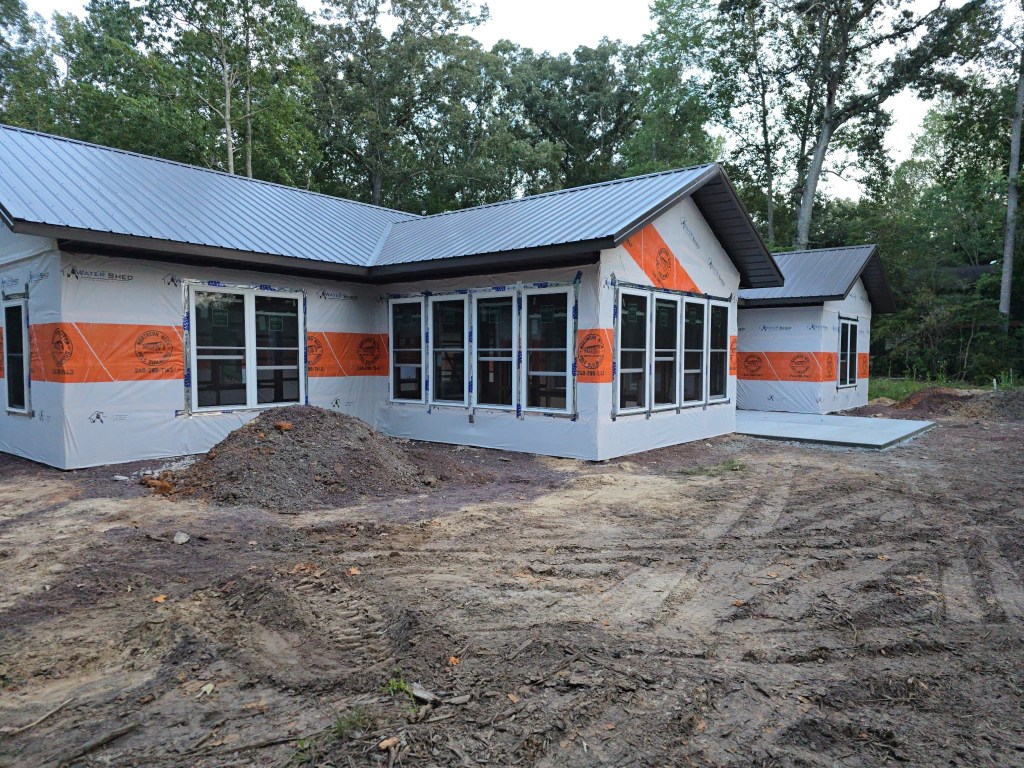 A house under construction featuring exposed building materials, visible through its incomplete exterior, with rubble scat...